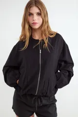 Chaqueta bomber rústica color negro con cuello redondo y cierre frontal de metal.