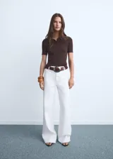 Jeans blancos de tiro alto con diseño acampanado y bajo deshilachado, con cierre de cremallera y botón, trabillas para cinturón y bolsillos traseros.