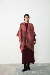 Ruana de tejido de punto con diseño teñido artesanalmente en tonos coral y marrón, con terminación de flecos en el ruedo.