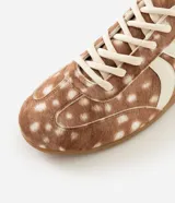Championes Satinato con diseño de animal print tipo ciervo, confeccionados en cuero sintético con textura suave. Presentan recortes laterales en tono crema, cierre con cordones y suela de goma antideslizante.