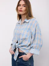Camisa de manga larga con estampado a cuadros en tonos celeste, beige y blanco, de corte oversize, con cuello clásico, cierre frontal de botones y un bolsillo aplicado en el pecho.
