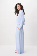 Pijama de algodón a rayas celestes y blancas, compuesto por una camisa de manga larga con botones y un pantalón largo de corte ancho.