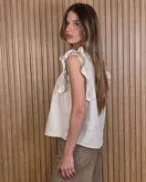 Musculosa color beige con cuello en V, alforzas frontales y mangas sin mangas con volados.