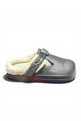 Zueco tipo pantufla color gris, con interior forrado en corderito sintético crudo, tira ajustable con hebilla metálica lateral y suela de goma.