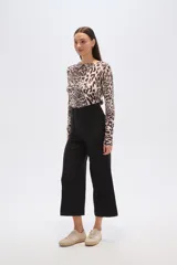 Pantalón negro de tiro alto, corte ancho y largo cropped (por encima del tobillo). Presenta un pliegue marcado vertical en el frente de cada pierna.