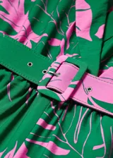 Mono largo con estampado tropical en tonos verdes y rosados, cuello con solapas, sin mangas y cinturón desmontable con hebilla forrada. Cierre con botones en el cuello.