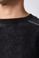 Buzo de cuello redondo con calce oversize, confeccionado en frisa de algodón con efecto de lavado gastado. Presenta costuras a contratono visibles y diseño de recortes en los hombros y mangas.