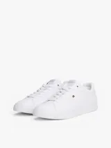 Zapatillas de tenis de corte bajo de la marca Tommy Hilfiger, confeccionadas en piel napa de color blanco. Presentan cordones, punta redonda, suela de goma y detalles distintivos como un pequeño logo esmaltado en el lateral y el nombre de la marca en la lengüeta.
