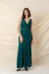 Vestido largo de fiesta en encaje color verde esmeralda, con escote en V, breteles anchos y falda con godets de tul. Presenta detalles de bordado con brillo en toda la prenda.