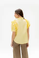 Camisa celeste de lino con cuello mao y mangas cortas abullonadas con volados. Cierre frontal con botones.