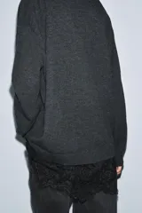 Jersey de punto con escote en pico y manga larga, con detalle de encaje en el bajo.