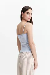 Musculosa de tiras finas color amarillo pálido, con textura elastizada y volados en el ruedo.