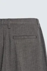 Pantalón de vestir con corte flare y ajuste relajado, confeccionado en tejido con viscosa y patrón de espiga. Cuenta con bolsillos frontales, bolsillos traseros de vivo y cierre frontal con cremallera y botón.