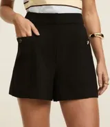 Short sastre de cintura alta con estructura definida, bolsillos laterales decorados con tachuelas metalizadas y recortes delanteros con costura aparente.