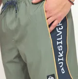 Short de baño Quiksilver de color verde militar, confeccionado en poliéster reciclado de secado rápido. Presenta cintura elástica con cordón ajustable contrastante, bolsillos laterales y una franja lateral con inscripción de la marca.