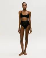 Top de lencería tipo bralette confeccionado en encaje negro, con breteles finos ajustables y diseño de escote redondo.