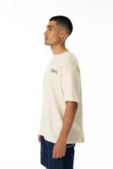 Remera color crudo de algodón con estampado en la espalda de cuatro recuadros con figuras de estilo Keith Haring y la palabra "VERNAL" en la parte superior.