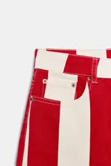 Jeans de tiro medio y corte tapered, con diseño de rayas verticales a contraste en color rojo y blanco. Cuenta con trabillas en la cintura, cinco bolsillos y cierre frontal con cremallera y botón metálico.