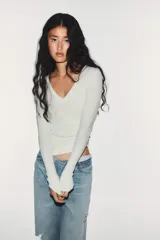 Jeans de mezclilla de tiro medio, corte wide leg y diseño relaxed. Presenta detalles rotos y desgastados en las piernas, y una cinturilla doblada superpuesta con trabillas y cierre frontal con cremallera y botón metálico.