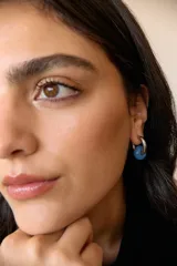 Aros de argolla en acero quirúrgico con dije de piedra natural en tono azul.