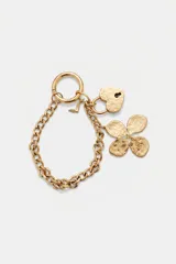 Llavero de metal dorado con cadena de eslabones y argolla con cierre de mosquetón. Incluye dijes colgantes con textura martillada: un candado en forma de corazón, un trébol de cuatro hojas y un pequeño dije con forma de ave.