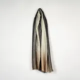 Pashmina de tejido ligero con diseño degradado que transita desde el negro hasta el beige, con sutiles destellos dorados brillantes en toda la superficie y bordes con flecos.
