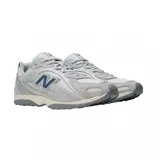 Championes urbanos New Balance modelo 204L, color gris con detalles en azul marino. Presentan una combinación de malla y gamuza, con el logo lateral característico y suela de goma con relieve.