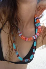 Pack de dos collares multicapa compuestos por cuentas de resina de diferentes formas y tamaños, en tonos turquesa, naranja, rojo, rosa y lila, con detalles rayados. Cierre de mosquetón metálico.