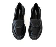 Mocasín de cuero negro con diseño de punta cuadrada y detalle acolchado en la pala. Cuenta con un tacón bajo y cuadrado.