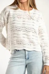 Sweater de punto calado con diseño de ondas horizontales, cuello redondo y mangas largas. Presenta un corte oversize y acabado en color blanco.