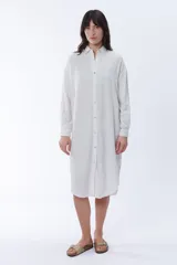 Vestido camisero blanco de lino, corte oversize, con cuello camisero, mangas largas y cierre frontal con botones.