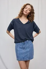 Falda de denim blanca de corte recto con bolsillos delanteros aplicados, costuras pespunteadas a contratono y cierre frontal con botón y cremallera.