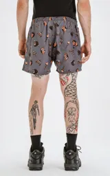 Short de baño gris con estampado de estilo tatuaje en tonos naranja y negro, con cintura elástica y cordón ajustable. Cuenta con cuatro bolsillos y está confeccionado en textil plano liviano de secado rápido.