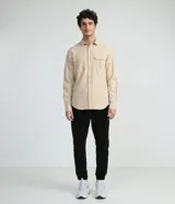Camisa de manga larga color beige, con cuello camisero y dos bolsillos frontales con cierre en solapa.