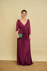 Vestido largo bordó de fiesta, con escote en V pronunciado, nudo drapeado en la cintura y tajo frontal. Las mangas son tres cuartos en tul translúcido con detalles sutiles.