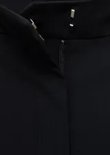 Pantalón de tiro medio color negro, de diseño recto y largo, con trabillas en la cintura, dos bolsillos laterales y cierre oculto con botón, gancho y cremallera.