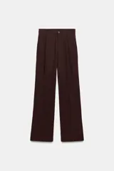 Pantalón de tiro alto confeccionado en tejido fluido, con diseño de corte recto y holgado. Presenta pliegues frontales, trabillas para cinturón, bolsillos laterales y cierre frontal con botón.