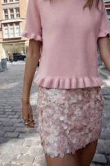 Falda corta de corte recto, completamente cubierta de lentejuelas redondas color rosa pálido o nude. Posee forro interior y cierre lateral oculto.