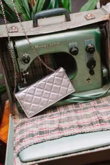 Cartera de cuero color marrón claro, con diseño capitoneado y cadena metálica plateada removible. Tiene ranuras interiores para tarjetas y documentos, y forro textil rojo.