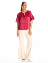 Blusa de satén color verde oliva, con cuello redondo y escote en V. Presenta mangas cortas con tres capas de volados superpuestos.