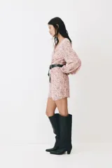 Vestido corto de gasa arrugada en color rosado con estampado floreado, escote en V y costura fruncida central con botones decorativos forrados. Cuenta con mangas globo largas con puños elásticos y cierre oculto en la espalda.