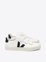 Championes urbanos Veja modelo Recife, color blanco con detalles en negro. Diseño de caña baja con cierre de tres tiras de velcro, confeccionados en cuero ChromeFree con suela de caucho.