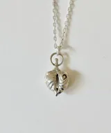 Collar de plata con cadena fina y dije en forma de corazón texturizado con detalles esculpidos.
