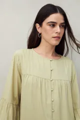 Camisa verde claro de silueta relajada, con botones forrados a tono, canesú con pequeñas tablas y mangas amplias con puño elastizado.