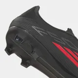 Championes de fútbol Adidas F50 League para terreno firme y multisuperficie. Presentan un diseño en color negro con detalles en rojo y blanco, parte superior Fiberskin con estampado Sprintgrid y suela Sprintplate 360 para mayor tracción y velocidad.