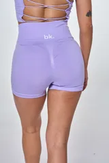 Conjunto deportivo de dos piezas en color lila, compuesto por un top de breteles finos con diseño acanalado y logo estampado, y un short de tiro alto de calce ajustado.