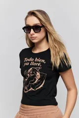 Remera negra de manga corta, con corte ajustado y estampa frontal en tono rosado que dice "Todo bien ya lloré" junto con un personaje ilustrado.