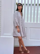 Vestido amplio de lino color verde lima, con cuello mao y abertura frontal con botones de coco. Presenta un diseño con canesú fruncido y volados en los puños de las mangas largas.