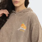 Canguro con capucha de efecto lavado, color marrón, con bolsillo frontal tipo canguro y pequeño estampado de una naranja con la palabra 'Juiced' en el pecho.