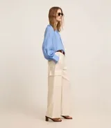 Pantalón wide leg color beige confeccionado en sarga sastrería, de cintura alta, sin estampa y con bolsillos cargo en los laterales.